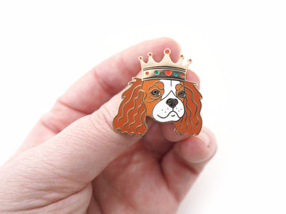 A photo of a hand holding a Blenheim Cavalier King Charles Enamel Pin