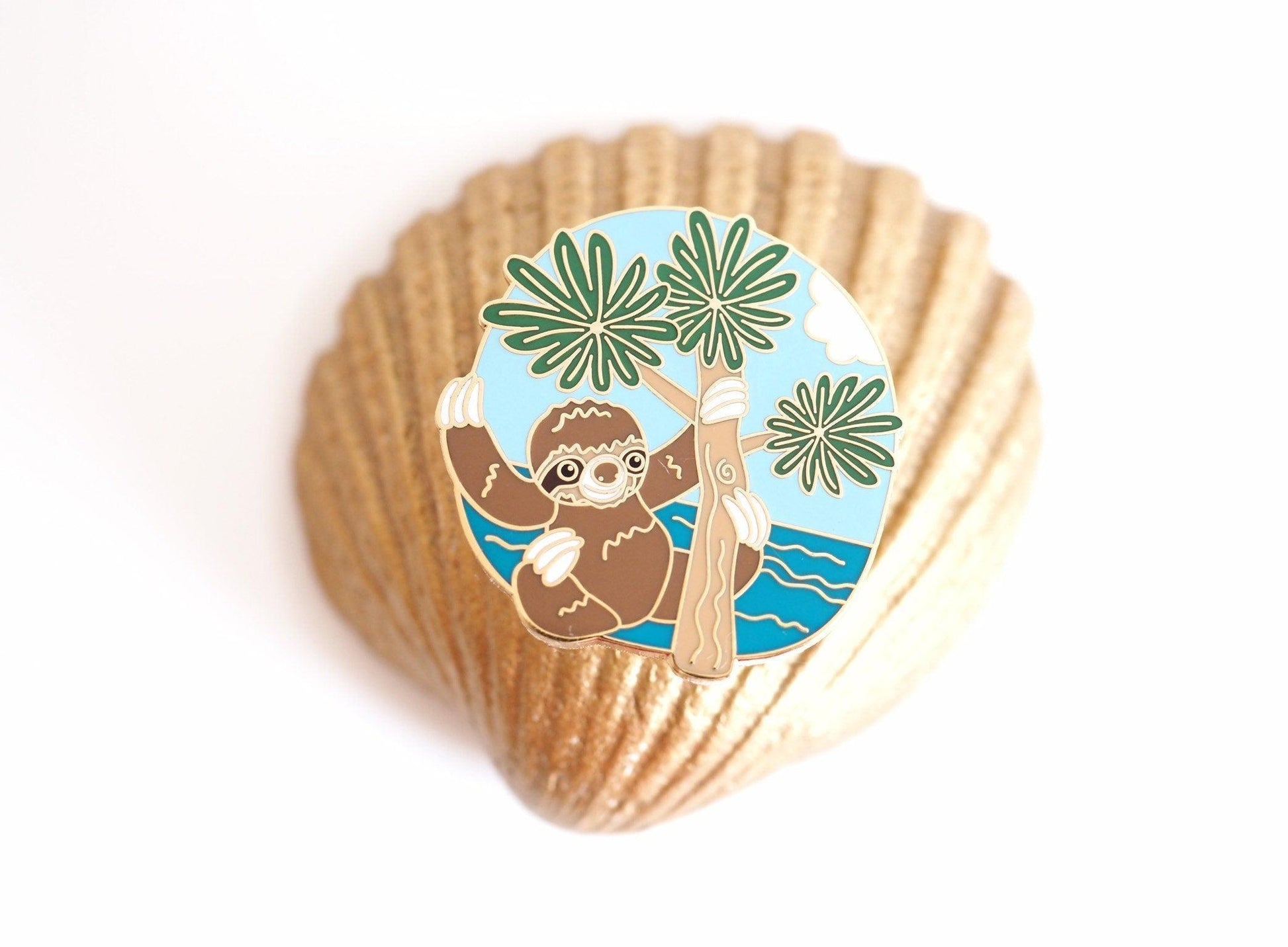 A photo of a sloth enamel pin
